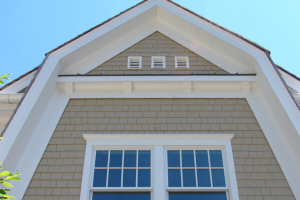 Beachgrass solid color prefinished cedar shingle siding on a front gable with bright white trim, a double window, and three small gable vents.