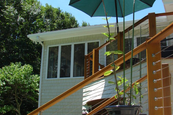 navajo-white-solid-color-prefinished-cedar-shingle-siding-pool-deck-wood-cable-railing Navajo White solid color prefinished cedar shingle siding on a poolside home exterior with large windows, white trim, and a wood-and-cable stair railing.
