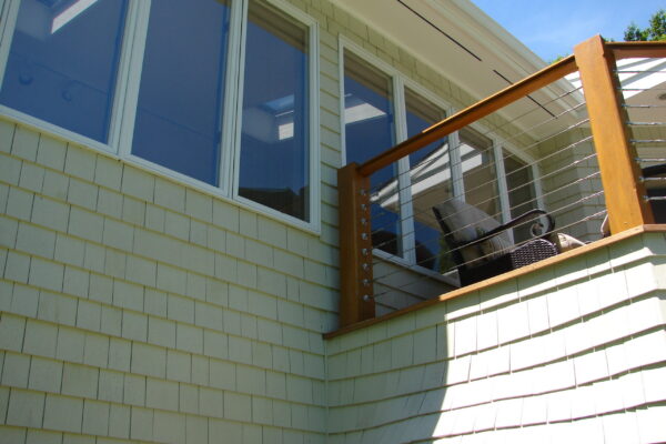 navajo-white-solid-color-prefinished-cedar-shingle-siding-poolside-deck-stairs Navajo White solid color prefinished cedar shingle siding on a mid-century home with a second-story deck, wood-and-cable railings, and a backyard pool.