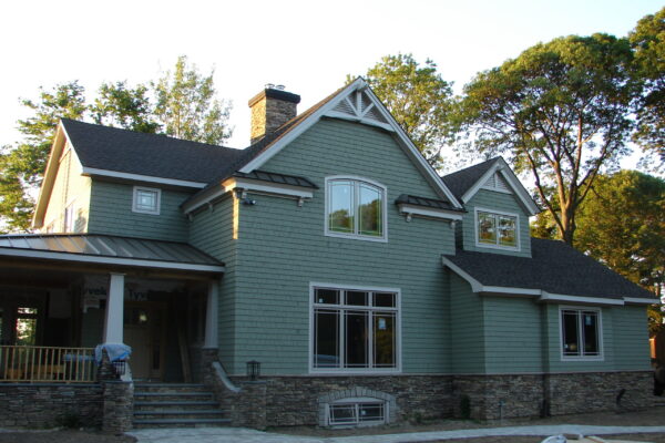 Sycamore solid color prefinished cedar shingle siding on a craftsman-style home with white trim, a dark shingle roof, and a stone foundation.