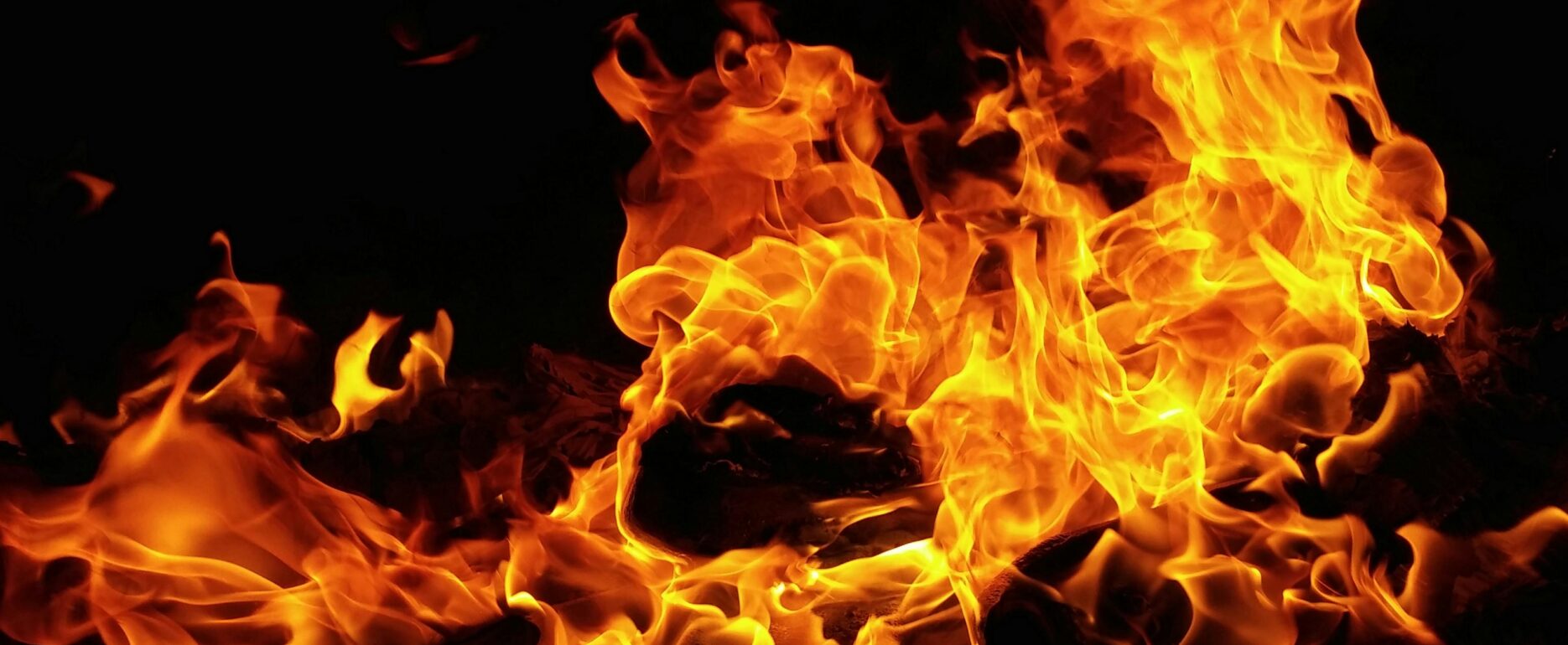 Bright orange flames rising from a fire against a black background.